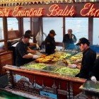 Un restaurant pe o barcă de pescuit în piața Eminönü din Istanbul oferă celebrul balik ekmek, un sandwich cu pește proaspăt fript, servit direct din mare, într-o atmosferă vibrantă și autentică.