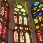 În interiorul Sagradei Família, vitraliile colorează piatra în roșu, verde și albastru, transformând coloanele inspirate de copaci în pădurea sacră de lumină imaginată de Gaudí.