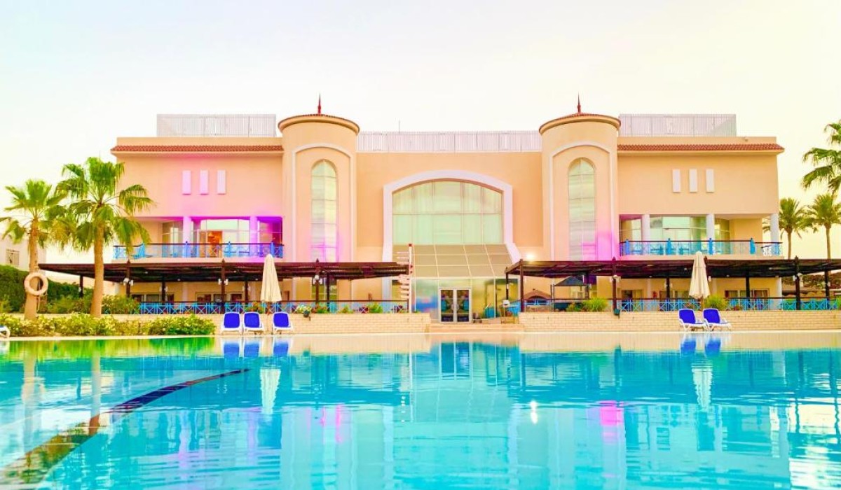 Ivy Cyrene Island Aqua Park Resort - Vedere aeriană a piscinei principale și a celor trei clădiri ale resortului, cu barul piscinei în centrul acesteia evidențiat.