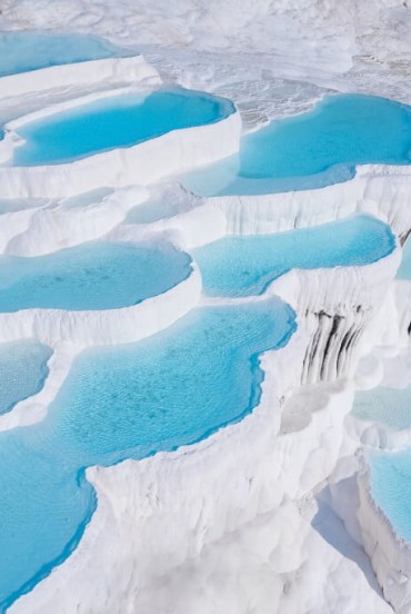 Terase de travertin alb la Pamukkale cu piscine naturale bogate în minerale vindecătoare, un peisaj unic și istoric.