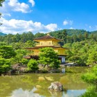 Vedere splendidă a Pavilonului de Aur (Kinkaku-ji) din Kyoto, un templu auriu înconjurat de natură, reflectat într-un iaz ce-i accentuează frumusețea și armonia peisajului japonez.