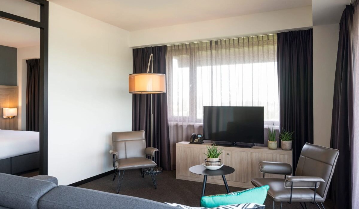 Adagio Amsterdam City South - Livingul Junior Apartment dispune de un colț TV cu canale prin satelit, o canapea confortabilă și două fotolii, creând un spațiu primitor, ideal pentru relaxare.