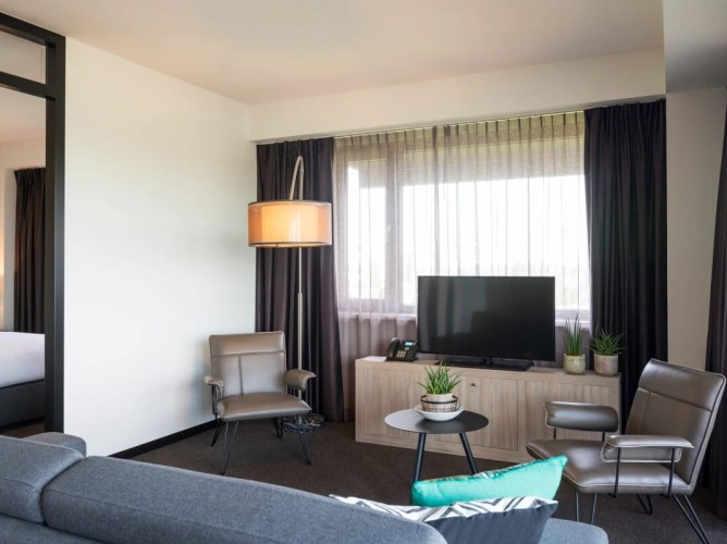 Adagio Amsterdam City South - Livingul Junior Apartment dispune de un colț TV cu canale prin satelit, o canapea confortabilă și două fotolii, creând un spațiu primitor, ideal pentru relaxare.
