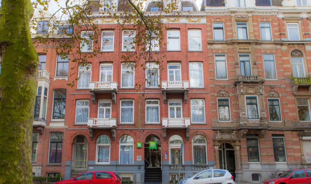 ibis Styles Amsterdam City - Stil clasic de secol XIX: ibis Styles Amsterdam City are o fațadă din cărămidă roșie și o atmosferă retro elegantă, cu ferestre mari în arc la parter, încadrate de ornamente decorative și frontoane.