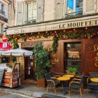 Un restaurant parizian tipic de pe Rue Mouffetard, în Cartierul Latin, își întâmpină oaspeții cu mese în aer liber, arome îmbietoare și atmosfera animată a străduțelor istorice din Paris.