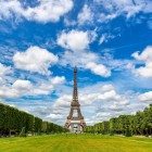 Întinderea verde a Champ de Mars se deschide ca un covor imens de iarbă, străbătut de alei umbrite și flori colorate, în timp ce Turnul Eiffel domină elegant fundalul.