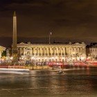 Noaptea, Place de la Concorde strălucește în lumini aurii ce se reflectă pe asfaltul umed, în timp ce obeliscul se înalță în centru, un custode impunător și tăcut al pieței.