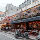 Cafenea tipic pariziană decorată cu flori și mese în aer liber pe Rue des Abbesses, Paris, Franța.
