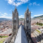 Vedere a turnurilor neogotice ale Bazilicii Votului Național din Quito, simbol al capitalei Ecuadorului, cu orașul desfășurat pe fundal.