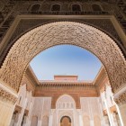Detalii ale intrării principale a Medresei Ben Youssef: un arc măreț în formă de potcoavă, decorat fin cu sculpturi din lemn de cedru.