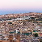 Vederea panoramică asupra orașului Fès dezvăluie medina străveche, acoperișurile roșii și minaretele - un mozaic fascinant de istorie, cultură și arhitectură tradițională.