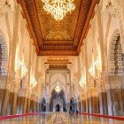Interiorul Moscheii Hassan II surprinde prin navata sa măreață, decorată cu incrustații din lemn, stucaturi rafinate și candelabre de cristal care răspândesc o lumină caldă și învăluitoare.