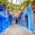 O alee pitorească albastră din Chefchaouen șerpuiește printre pereți vopsiți și magazine ascunse, unde arta locală și viața cotidiană se contopesc într-o atmosferă autentică și magică.
