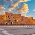 Kasbah-ul Taourirt din Ouarzazate se ridică impunător, cu turnuri crenelate și pereți ocru, mărturie a arhitecturii tradiționale marocane.