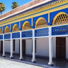 Sub porticul Palatului Bahia, arcadele sculptate și pictate manual încadrează mozaicuri zellige geometrice, într-un triumf de albastru cobalt, verde și ocru.