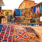 În soukul în aer liber din Aït Ben Haddou, tarabele oferă obiecte de artizanat local, țesături, covoare și ceramică, printre alei și curți tradiționale.