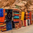 În souq-ul din Tinghir, covoarele marocane cu culori vii și modele tradiționale decorează magazinele, exprimând meșteșugul local autentic.