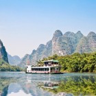 Croazieră pe apele limpezi ale râului Li din Guilin, printre munți carstici și sate tradiționale care reflectă istoria și natura locală.
