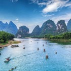 Bărci turistice mici pe râul Li din Guilin, printre munți carstici și sate tradiționale, oferă priveliști autentice ale sudului Chinei.