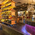 Elegant wine bar la Ramada Istanbul Pera, cu iluminare caldă și rafturi din lemn, pentru o experiență de degustare unică și rafinată.