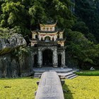 Podul care duce la Pagoda Bích Động traversează un mic curs de apă, oferind priveliști pitorești între reflexii pe apă și arhitectura tradițională a complexului.