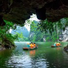 Explorarea peșterilor din Tam Cốc înseamnă descoperirea unor tuneluri de apă între munți de calcar și reflexii ale peisajului verde pe apele liniștite.