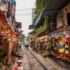 Șinele de tren din Hanoi trec printre case înguste și cafenele locale, creând un pasaj urban unic și fascinant în inima orașului.