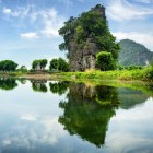 Un turn carstic se ridică deasupra apelor liniștite ale râului Ngo Dong din Tam Cốc, între reflecții perfecte și peisaje naturale uimitoare.