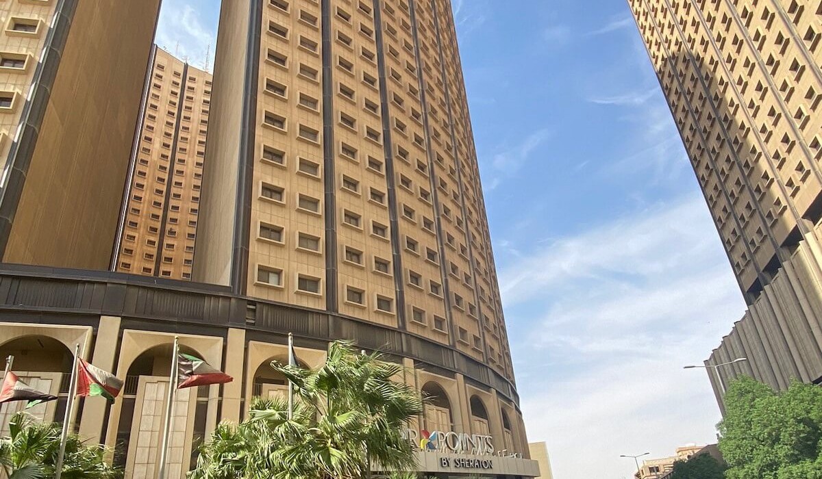 Four Points by Sheraton Riyadh Khaldia - Intrare elegantă cu arcade și fațadă aurie, logo-ul Four Points by Sheraton vizibil, palmieri și pereți de sticlă pentru o primire rafinată și călduroasă.