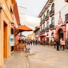 Artera principală din San Cristóbal de las Casas este o alee pietonală animată, flancată de clădiri coloniale colorate, cafenele în aer liber, magazine artizanale și o atmosferă autentică și vibrantă.