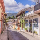 Stradă colonială din San Cristóbal, cu case colorate, balcoane cu flori și acoperișuri din teracotă, între munții Chiapas. Un colț autentic plin de farmec.
