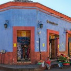 Vânzători ambulanți maya în fața fațadei colorate a unui magazin colonial din orașul San Cristóbal, Mexic.