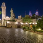 Palatul Shirvanshahilor noaptea, la Baku, impresionează prin cupolele și minaretele iluminate, între ziduri vechi și silueta modernă a orașului în fundal.