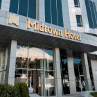 Exterior modern al Midtown Hotel din Baku, cu fațadă din sticlă, panouri deschise și intrare luminoasă. Inscripția aurie oferă eleganță și un stil contemporan rafinat.