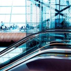 Interioare moderne ale Aeroportului din Baku, cu suprafețe vitrate mari, scări rulante elegante și un design futurist. Spațiile luminoase și liniile curbe creează o atmosferă rafinată și contemporană.