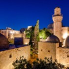 Vederea din spate a Palatului Shirvanshahilor din Baku evidențiază cupole elegante, minarete și arhitectură istorică iluminată, simbol al bogatului patrimoniu cultural al Azerbaidjanului.