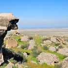 Peisaj semi-deșertic al peninsulei Absheron din Azerbaidjan, între stânci, pajiști și vedere la Marea Caspică, zonă istorică bogată în vestigii antice.
