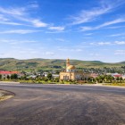 Fotografia arată moscheea din Mereze, Azerbaidjan, cu cupolă aurie în centrul satului, înconjurată de case și coline verzi, într-un peisaj rural autentic.