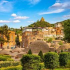 În inima orașului Tbilisi, cupolele băilor sulfuroase se ridică printre grădini îngrijite și case colorate, cu dealul și o biserică dominând panorama.