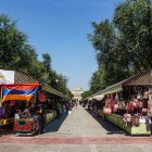 Piața Vernissage din Erevan cu tarabe de suveniruri artizanale, textile și obiecte tradiționale, plină de culori vii și atmosferă autentică sub cerul de vară.