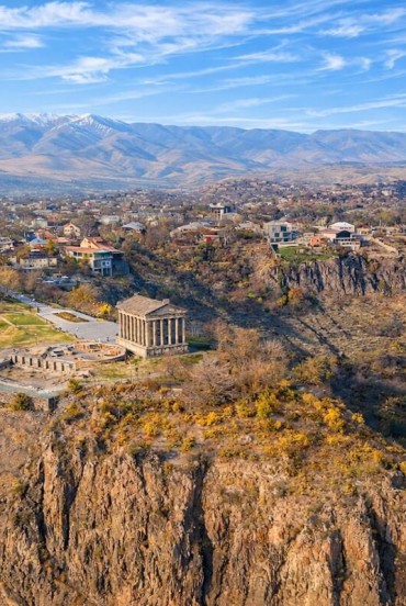 Vedere aeriană a Templului Garni din Armenia, situat pe marginea defileului Azat, înconjurat de munți și sate: unul dintre cele mai iconice și pitorești situri istorice din Caucaz.