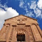 Fațada Mănăstirii Noravank, Armenia: basoreliefuri fine și cruci sculptate decorează intrarea, simbol al artei medievale armene și al spiritualității.