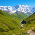 Peisaj montan din Svaneti cu văi verzi și vârfuri înzăpezite ale Caucazului. Natură neatinsă și priveliști spectaculoase ideale pentru drumeții și aventură.