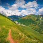 Potecă printre dealurile verzi din Svaneti, cu vedere spre vârfurile Caucazului. Un peisaj neatins, ideal pentru drumeții și priveliști spectaculoase.