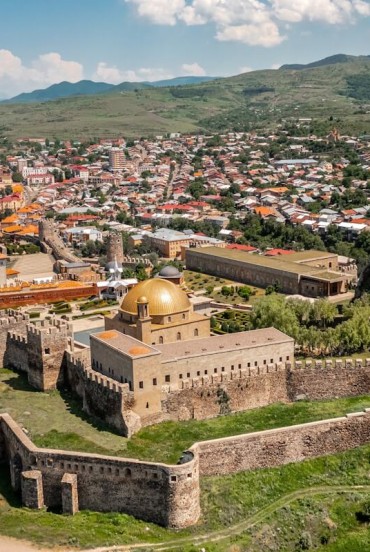 Vedere panoramica asupra Akhaltsikhe cu cetatea Rabati, ziduri medievale, turnuri si cupole aurii, inconjurata de dealuri verzi si peisaj autentic georgian.