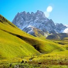 Vale verde și luminoasă la poalele Muntelui Chaukhebi, unde poteci șerpuite traversează pajiști alpine și duc spre vârfurile spectaculoase ale Caucazului georgian.