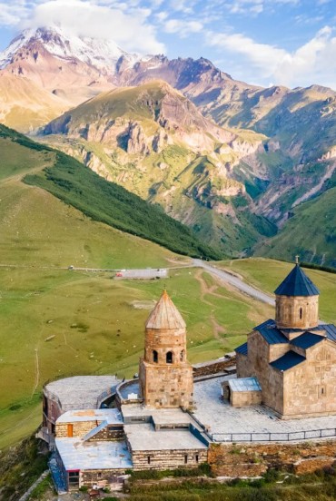 Biserica Sfânta Treime din Gergeti domină dealurile de deasupra Stepantsminda, privind peste văile din Kazbegi, cu Muntele Kazbek în fundal.