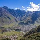 Vedere asupra Stepantsminda, așezată în vale la poalele Munților Caucaz, înconjurată de vârfurile impunătoare ale regiunii Kazbegi.