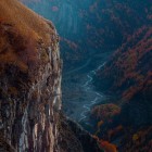 Priveliște asupra munților din Gudauri toamna, unde chei adânci, stânci abrupte și păduri arămii conturează peisaje spectaculoase în inima Caucazului georgian.
