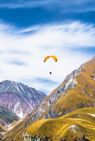 Parapantă printre vârfurile din Gudauri, unde zborul oferă o perspectivă unică asupra munților Caucazului și a panoramelor vaste din Georgia montană.